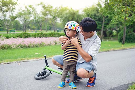 Parent putting bike helmet on child.