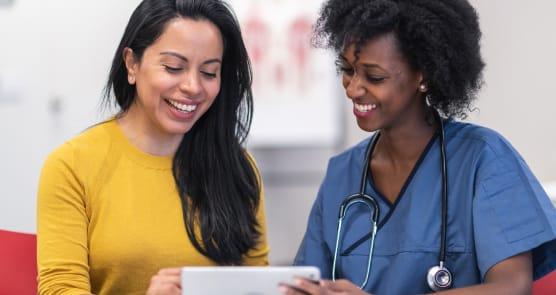 a woman wearing a yellow shirt smiles as she reviews a document with her healthcare provider