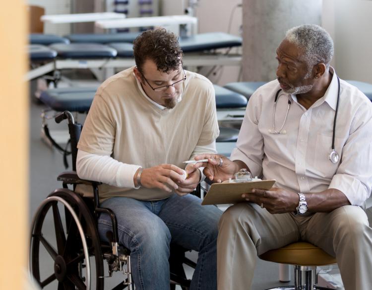 Man in wheelchair speaking with his provider.