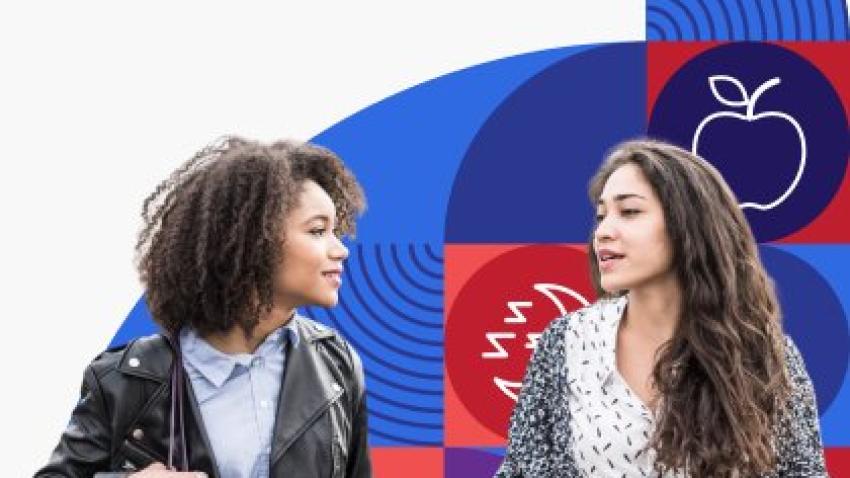 Two young women walk and talk together.